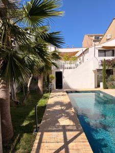 a swimming pool with a palm tree next to a building at La Maison De Ville - Piscine & SPA in Sète