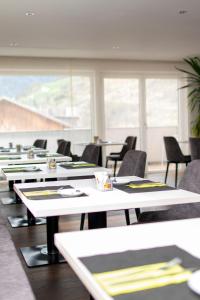 a row of tables and chairs in a room with windows at Lapis Monti Apartments & Suites in Burgusio