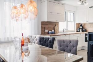 a white kitchen with a glass table and chairs at Kranichkieker in Zingst