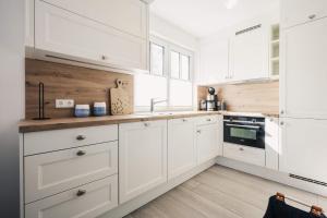 a white kitchen with white cabinets and wooden floors at Kranichkieker in Zingst +26 photos
