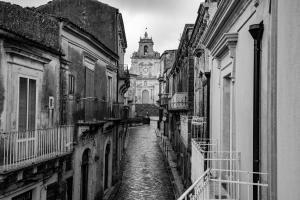 a black and white photo of an alley with a clock tower at Ghibellini Rooms in Palazzolo Acreide