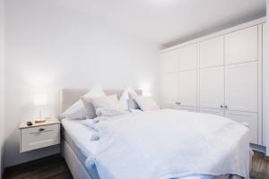 a white bedroom with a large bed with white cabinets at Kranichruf in Müggenburg +8 photos