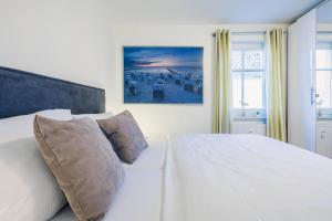 a bedroom with a white bed and a painting on the wall at Neuland in Zingst