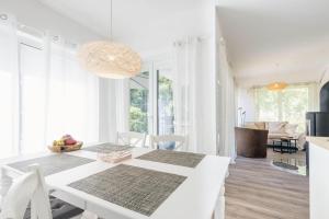 a white dining room with a white table and chairs at Sommersonne in Zingst