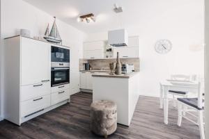 a kitchen with white cabinets and a table and a stool at Sommersonne in Zingst