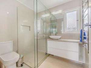 a bathroom with a toilet and a glass shower at Janet Street in Noosaville +10 photos
