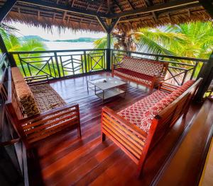 a balcony with benches and a table and palm trees at Le Lagon Bleu in Antsatrakolo