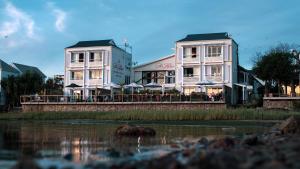 two buildings with tables and umbrellas next to a river at The Lofts Boutique Hotel in Knysna