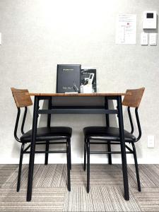 a desk with two chairs and a laptop on it at Room One in Aomori