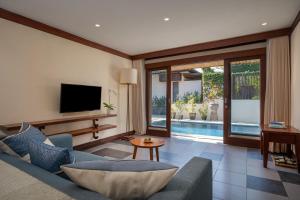a living room with a couch and a tv at Rama Residence Seminyak in Seminyak