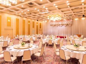 a banquet hall with white tables and chairs at Yatsushiro Grand Hotel in Yatsushiro