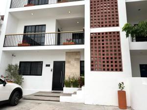 a white house with a white car parked in front of it at Casa DOS21 Boutique Apartments Playa Sur in Mazatlán