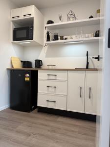a kitchen with white cabinets and a black refrigerator at Cozy Pakura Pad in Te Awamutu