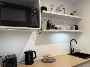 a kitchen counter with a microwave and a sink at Cozy Pakura Pad in Te Awamutu +4 photos