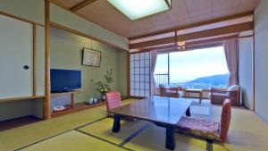 a living room with a table and chairs and a television at Hatoya Hotel in Ito