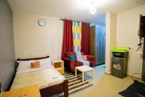 a bedroom with a bed and a couch and a chair at Vine Suites Mbarara - 1 Bed Studio Apartment Near LDC & City Centre - Quiet & Convenient in Mbarara