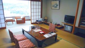 a living room with a table and chairs and a television at Hatoya Hotel in Ito +16 photos