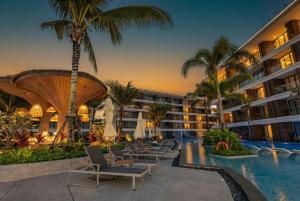 a resort with a pool and lounge chairs and palm trees at Sunshine Beach Layan by Beringela in Layan Beach