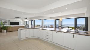 a kitchen with white cabinets and a view of the ocean at 'Aloha Beach Retreat' by HolidayCo in Norah