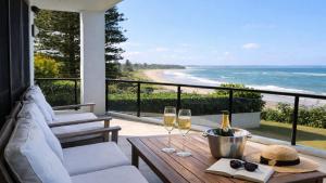 a balcony with a table with two glasses of wine at 'Aloha Beach Retreat' by HolidayCo in Norah +16 photos