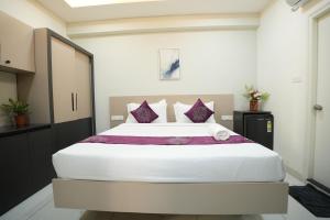 a bedroom with a large white bed with purple pillows at Hotel Flamount Arka Studios in Hyderabad