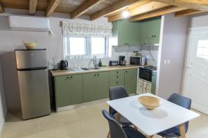 a kitchen with green cabinets and a table with chairs at RAVANIS Home in Áyios Pétros +33 photos