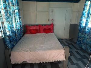 a small bed with red pillows in a room at Sarah House Rental in Clarin