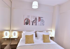 a bedroom with a bed with white sheets and yellow pillows at EREA Homes Apartments in Eretria +43 photos