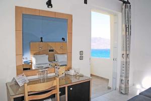 a room with a desk with a view of the ocean at Ermioni Hotel in Georgioupolis