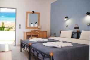 two beds in a bedroom with a view of the ocean at Ermioni Hotel in Georgioupolis