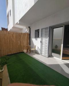 a small backyard with a green lawn at Résidence Nafissa Ezzahra Kelibia in Ḩammām al Ghazzāz