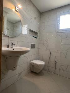 a white bathroom with a sink and a toilet at Résidence Nafissa Ezzahra Kelibia in Ḩammām al Ghazzāz +10 photos