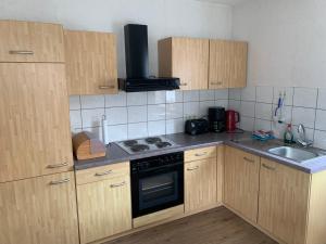 a kitchen with wooden cabinets and a stove top oven at Ferienwohnung Wehner in Seiferts