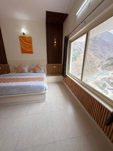 a bedroom with a bed and a large window at Mandola Stays in Chamoli