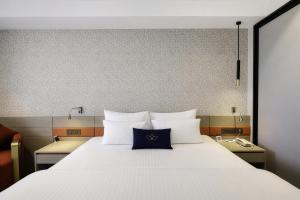 a large white bed with a blue pillow on it at Grand Continent Hotel, Near Sector 44, Gurugram in Gurgaon +33 photos