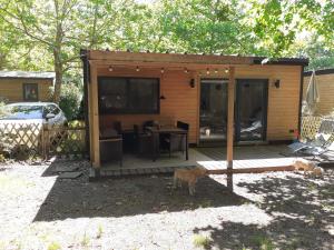a small cabin with a table and two cats in the yard at Chalet dans le camping l'Orée des Landes à Onesse et Laharie in Onesse-et-Laharie
