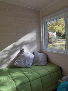 a small room with a green couch and a window at Chalet dans le camping l'Orée des Landes à Onesse et Laharie in Onesse-et-Laharie