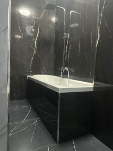 a bathroom with a sink and a black wall at Iceland Apartment in Tirana