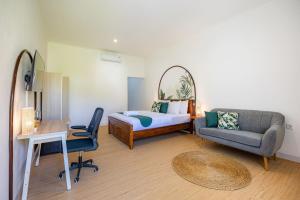 a bedroom with a bed and a couch and a chair at Cove Dahayu Sanctuary in Sanur
