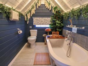a blue bathroom with a tub and a toilet at Applejacks Orchard in Holywell +32 photos