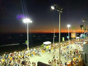 una multitud de personas de pie en una playa por la noche en Flat na Avenida Oceanica, en Salvador