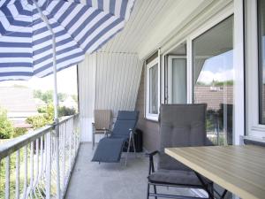 a porch with chairs and a table and an umbrella at Ferienhaus Haffliebe in Scharbeutz