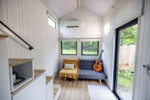 a tiny house with a blue couch and a guitar at Echidna by Tiny Away in Thoopara