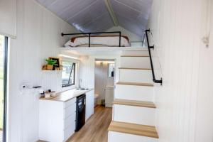 a tiny house with a staircase and a bunk bed at Echidna by Tiny Away in Thoopara