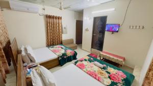 a bedroom with two beds and a mirror at Hotel Labbaik Three College Gate in Dhaka