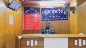 a man standing behind a counter in a restaurant at Hotel Labbaik Three College Gate in Dhaka
