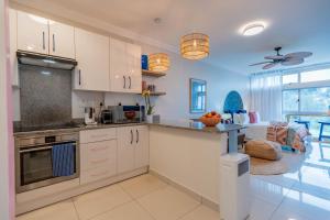 a kitchen with white cabinets and a living room at Alfomada in Umdloti
