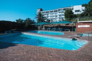 a large swimming pool with a hotel in the background at Alfomada in Umdloti