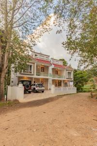a large house with a car parked in the driveway at Riyan Valley Resort in Ooty