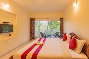 a bedroom with a large bed with a large window at Riyan Valley Resort in Ooty
